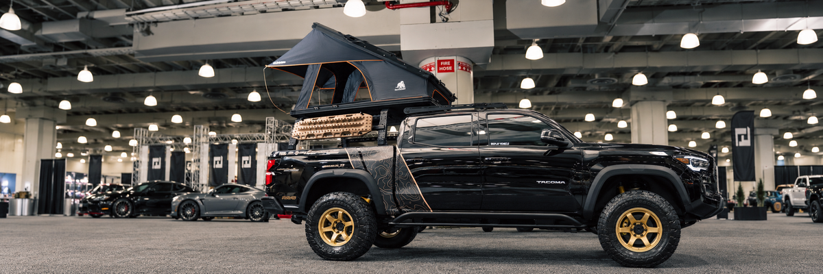 Full modified pickup with rooftop tent at an indoor show, AI-expanded photograph